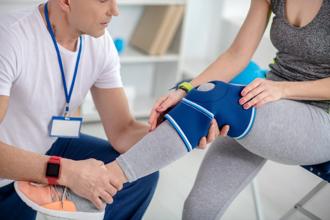 Male physiotherapist examining knee of female patient sitting on couch - lighthouse chiropractic | family chiropractic center | fort collins, co | experienced practitioner professionals | fort collins chiropractic care & massage therapy